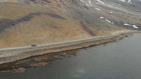 aerial view of suv going along road beside shandur lake in pakistan. slow motion dolly forward