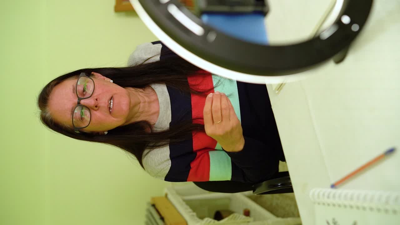 mujer madura hablando durante una reunión en línea en el teléfono inteligente - disparo vertical