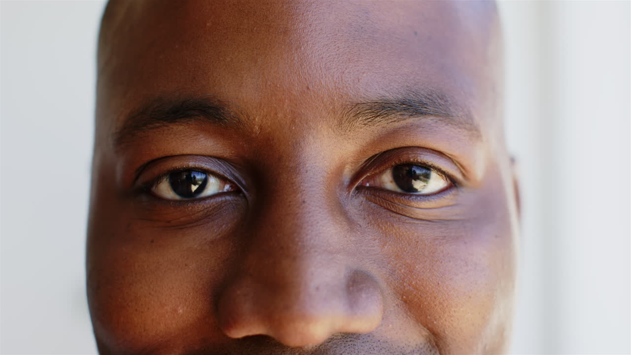 Homme afro-américain souriant regardant directement la caméra, gros plan des yeux et du visage