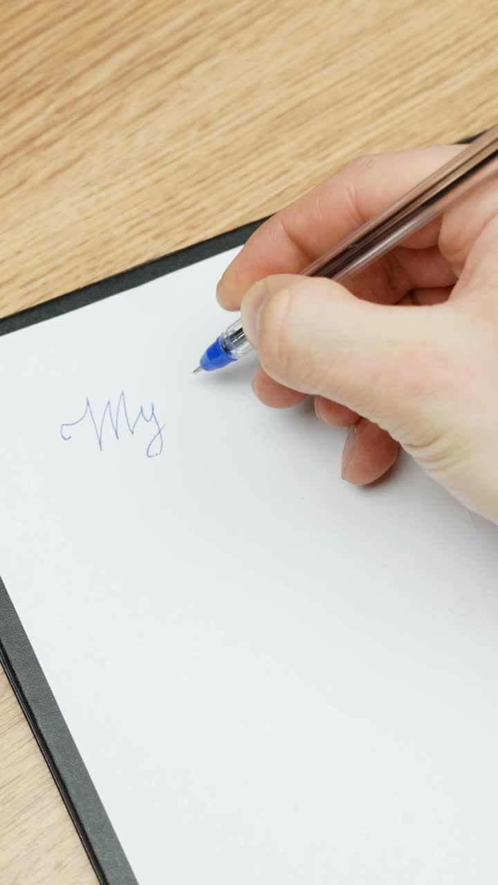 Hand writing “My plan” with a pen on white paper, close-up from above, calm and focused