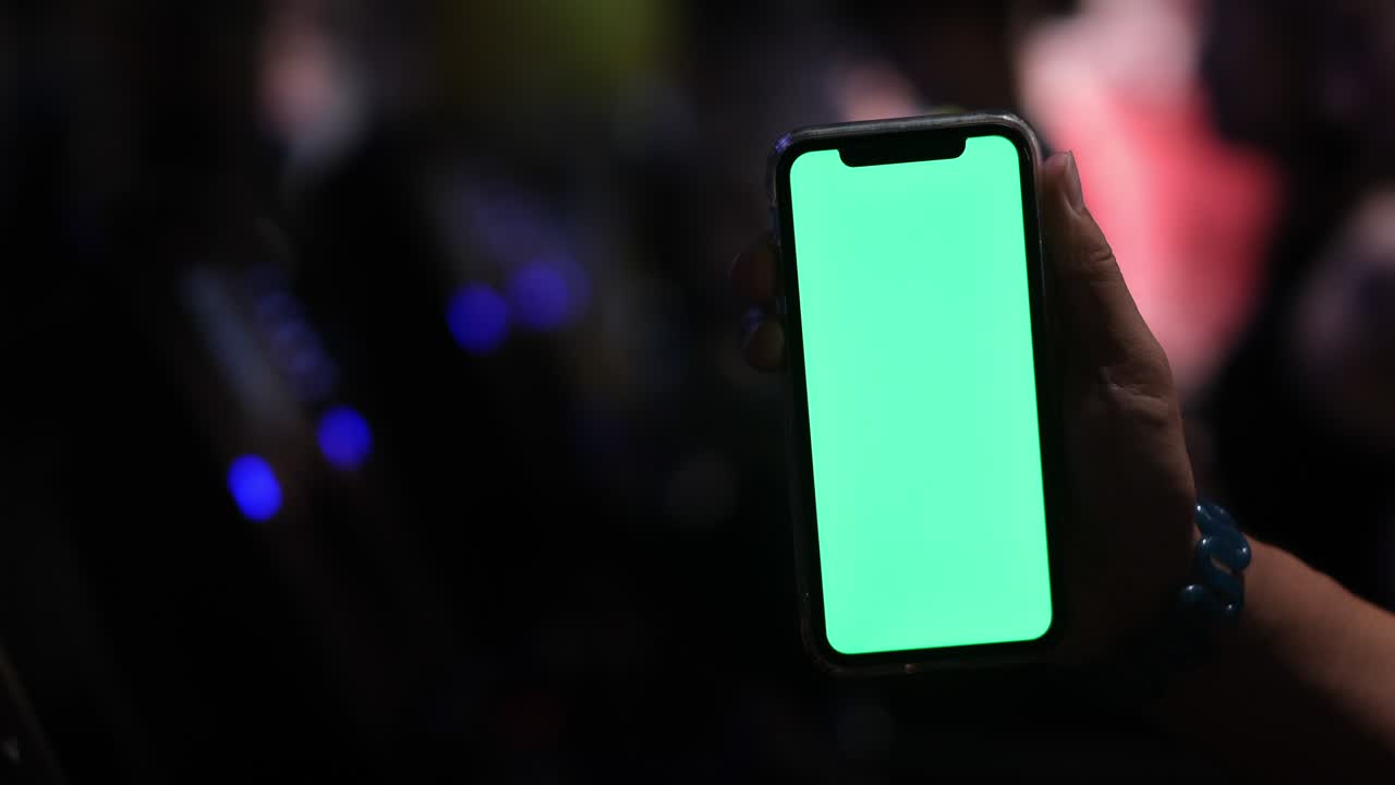 hand showing green screen smart phone while exercising on treadmill in gym room at night