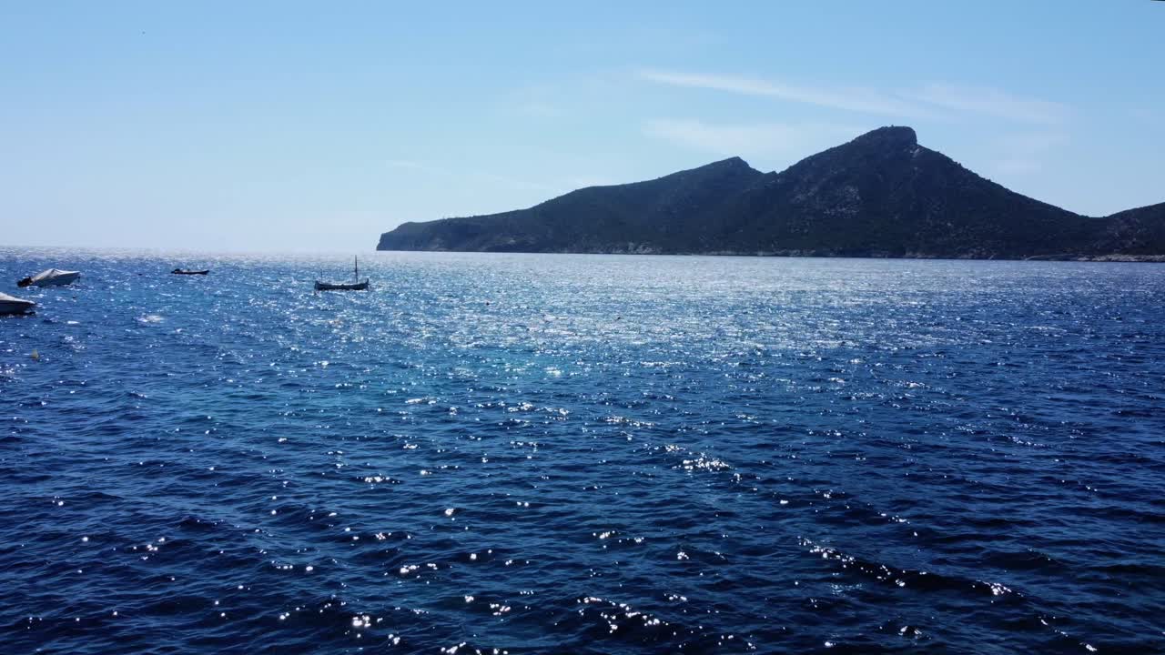 바람과 태양이 파도를 치는 동안 4k 바다와 배경에 있는 작은 보트에서 드론 촬영