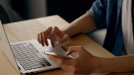 Mittelteil-Eines-Mannes,-Der-Auf-Dem-Smartphone-SMS-Schreibt-Und-Am-Schreibtisch-Einen-Laptop-Benutzt