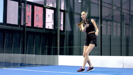 woman playing padel tennis on indoor court, focused and ready for action