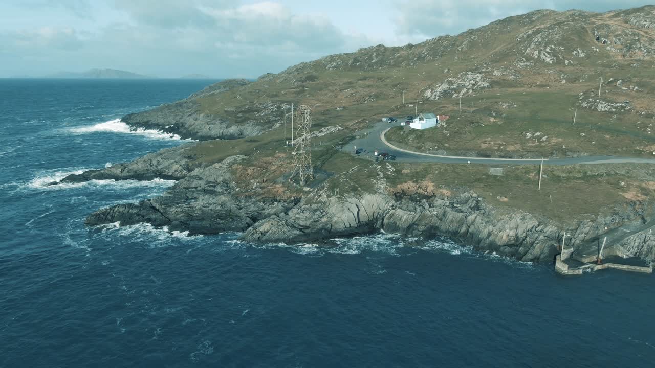 Aerial flight coming down towards rocky shore and cable car cabin with waves crashing on the shore line during cloudy day