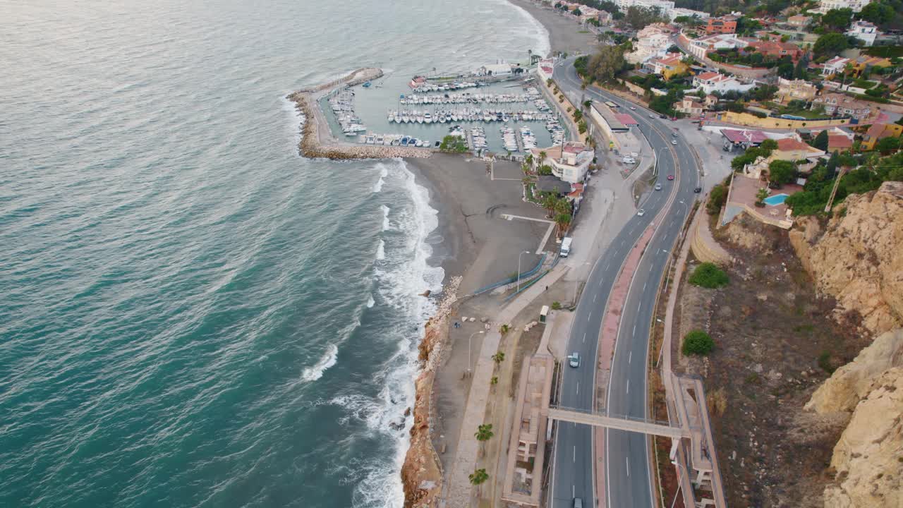 toma aérea de pájaros de automóviles en la carretera al lado del océano con el puerto deportivo de málaga en el fondo - arriba estático hacia abajo
