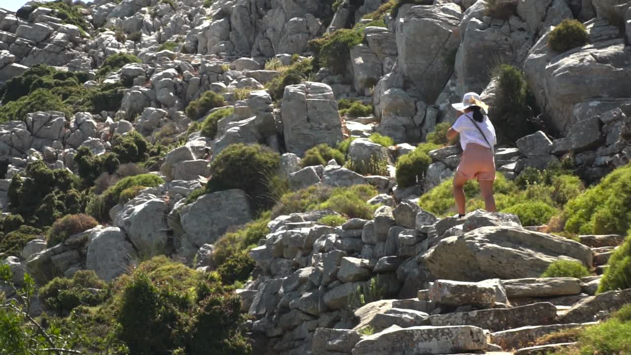 chica en traje de senderismo veraniego caminando por un paisaje rocoso árido mientras camina