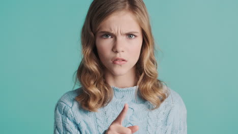 angry teenage caucasian girl making silence gesture in front of the camera.