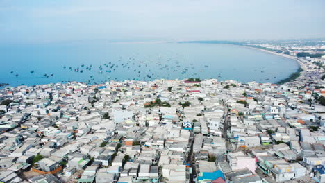 Aerial,-cramped-overcrowded-slum-houses-by-the-ocean-in-rural-Southeast-Asia