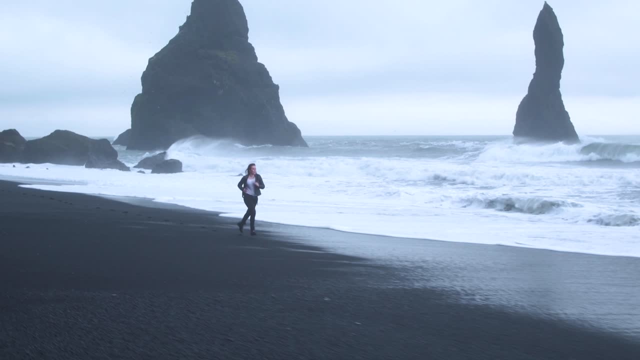 Desperate woman running on deserted beach. Aerial flying backwards