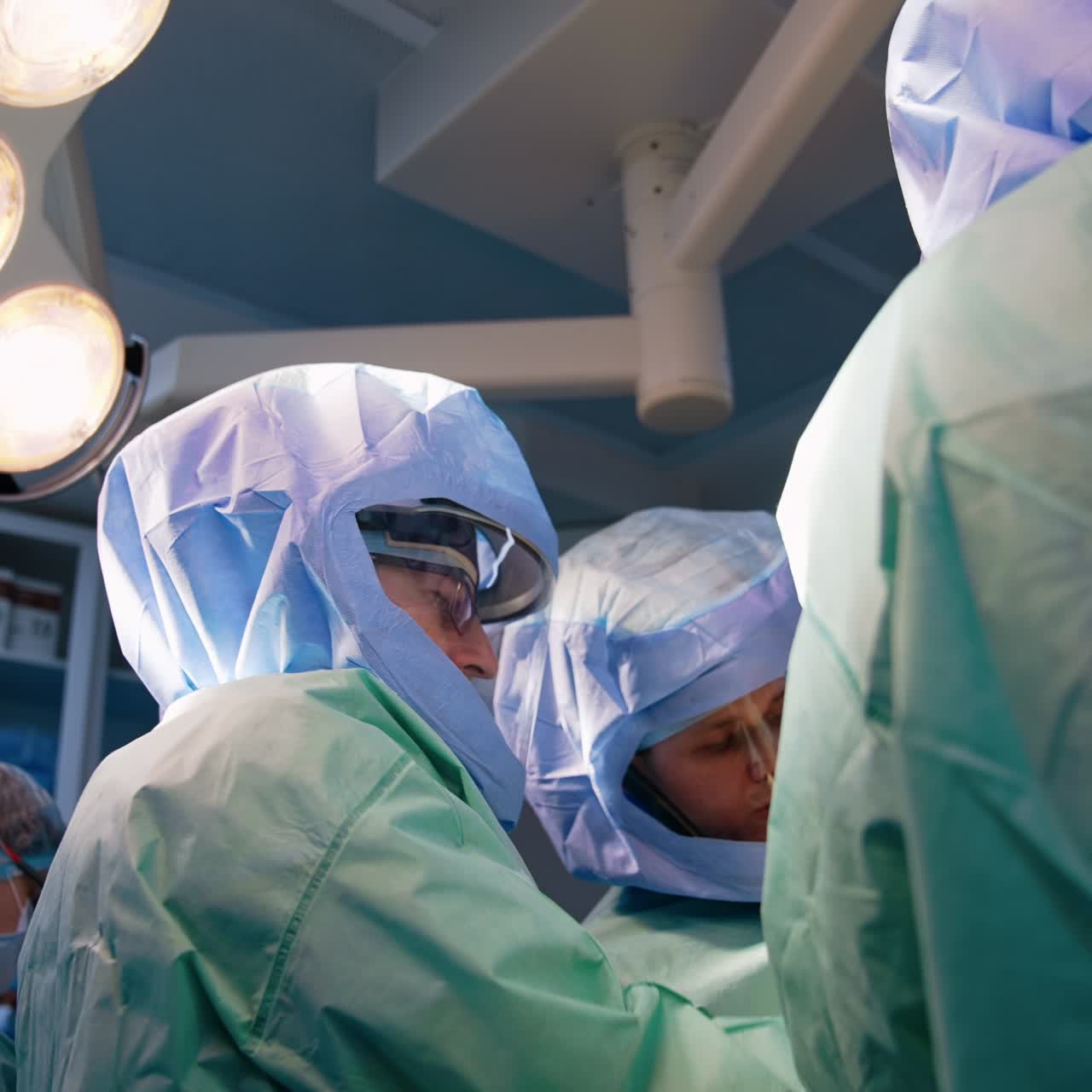 Surgeons in protective helmets perform operation. Doctors working in a team. Low angle view