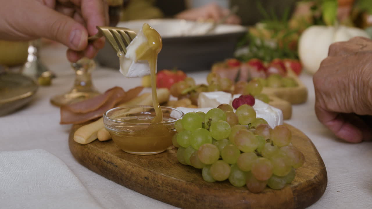 Cheese board with grapes, cheese, honey, ham and other appetizers