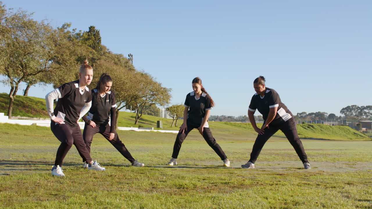 Stretching on field, female cricket team warming up before practice session