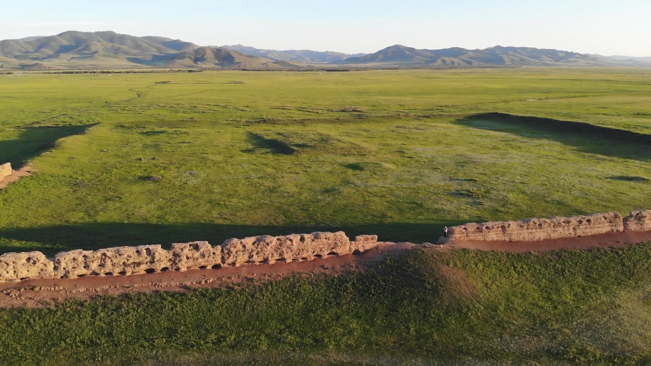 Luftfoto af ruinerne af en gammel stenmur i den vidtstrakte grønne mongolske steppe