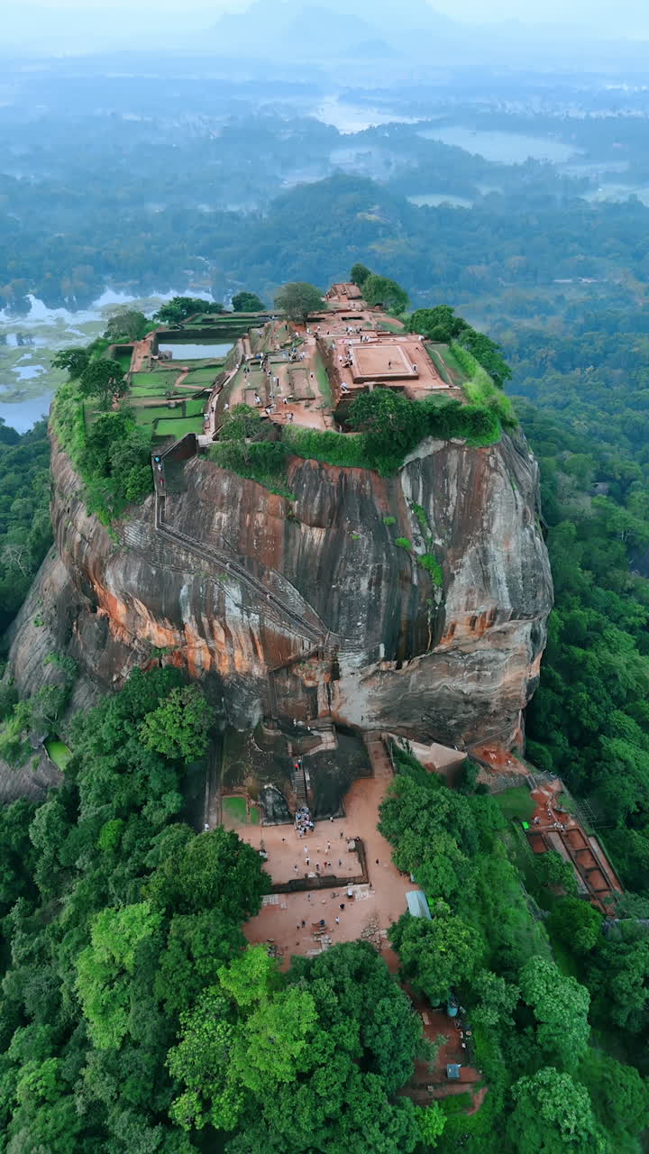 Beautiful rock with the ruins of Sigiriya fortress in Sri Lanka. Lots of tourist walk by the mountain top. Aerial perspective. Vertical video.