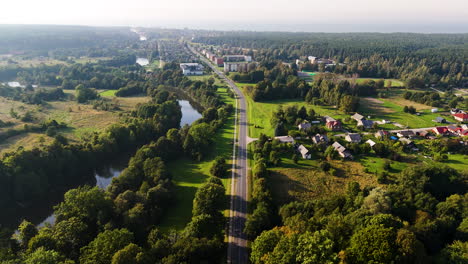 Green countryside with endless road on sunny day, aerial view