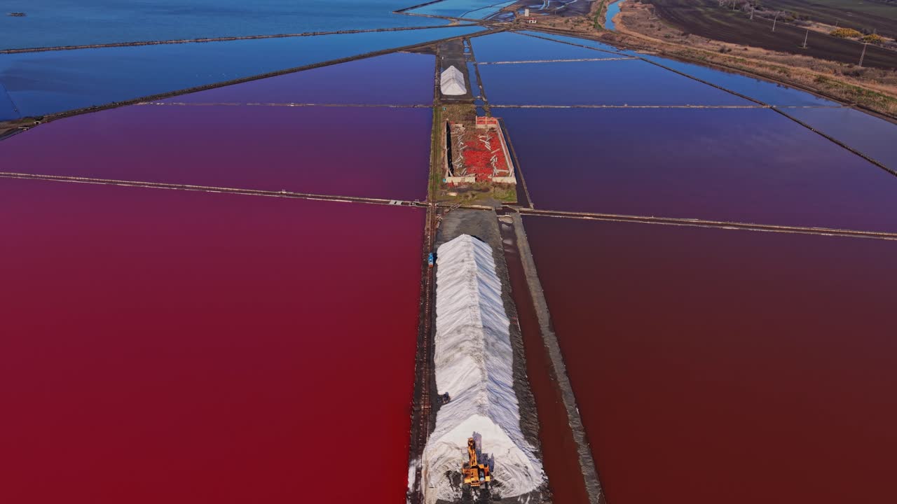 Salt production process near colorful salt ponds during daylight hours