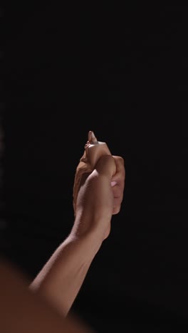 close up of woman squeezing tube of make up until contents squirt out shot on black background 1