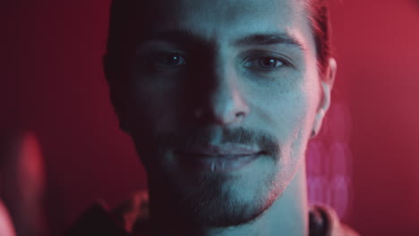 close-up portrait of a smiling man with neon lighting