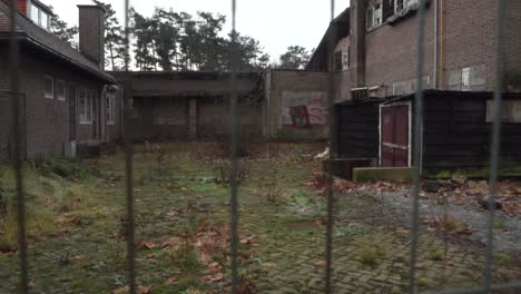 abandoned building in a courtyard, enclosed by a fence