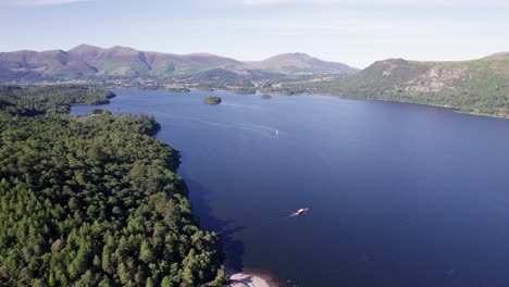 high drone shot flying left over derwent water with boats on the lake on a sunny day, lake district, cumbria, uk