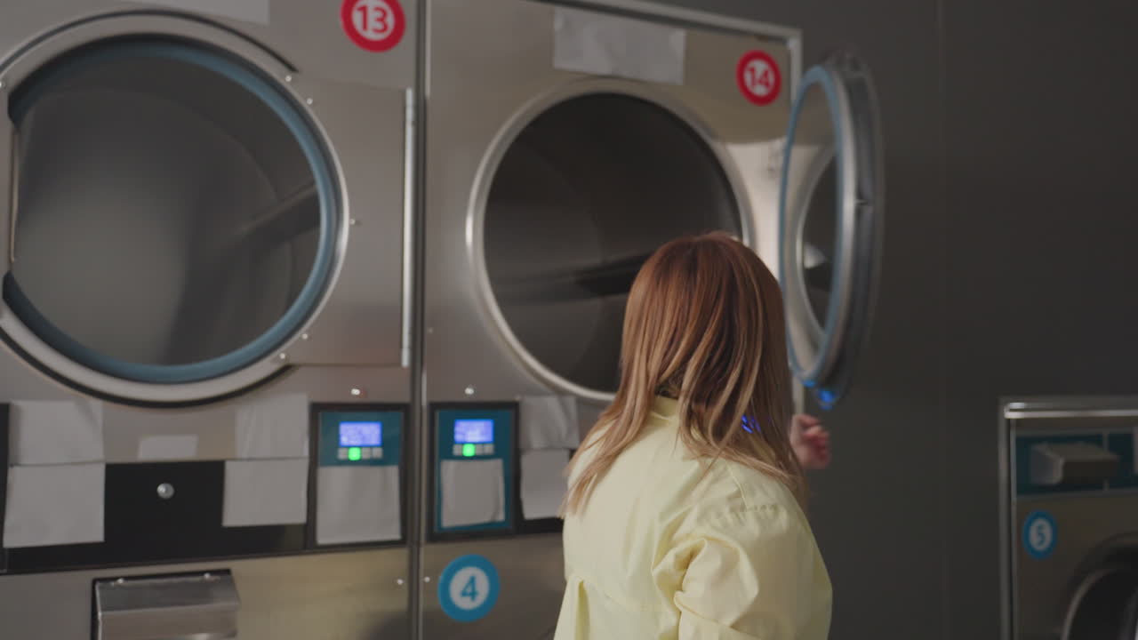 Laundry owner closes washer door, smiles with relief after loading start, stainless machines glow in modern laundromat, back view gesture confirms job finished, clean service workflow, interior mood