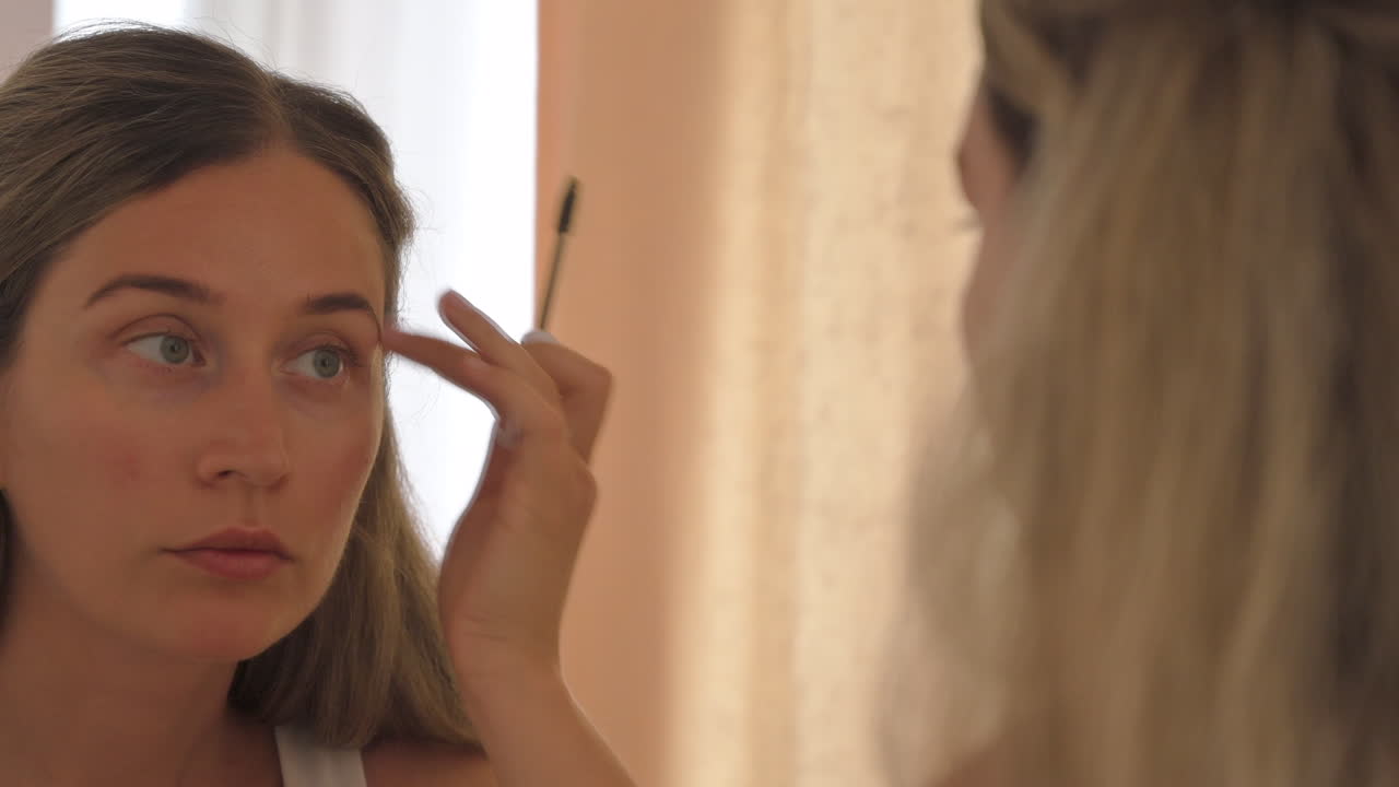 Woman shaping her eyebrows in the mirror