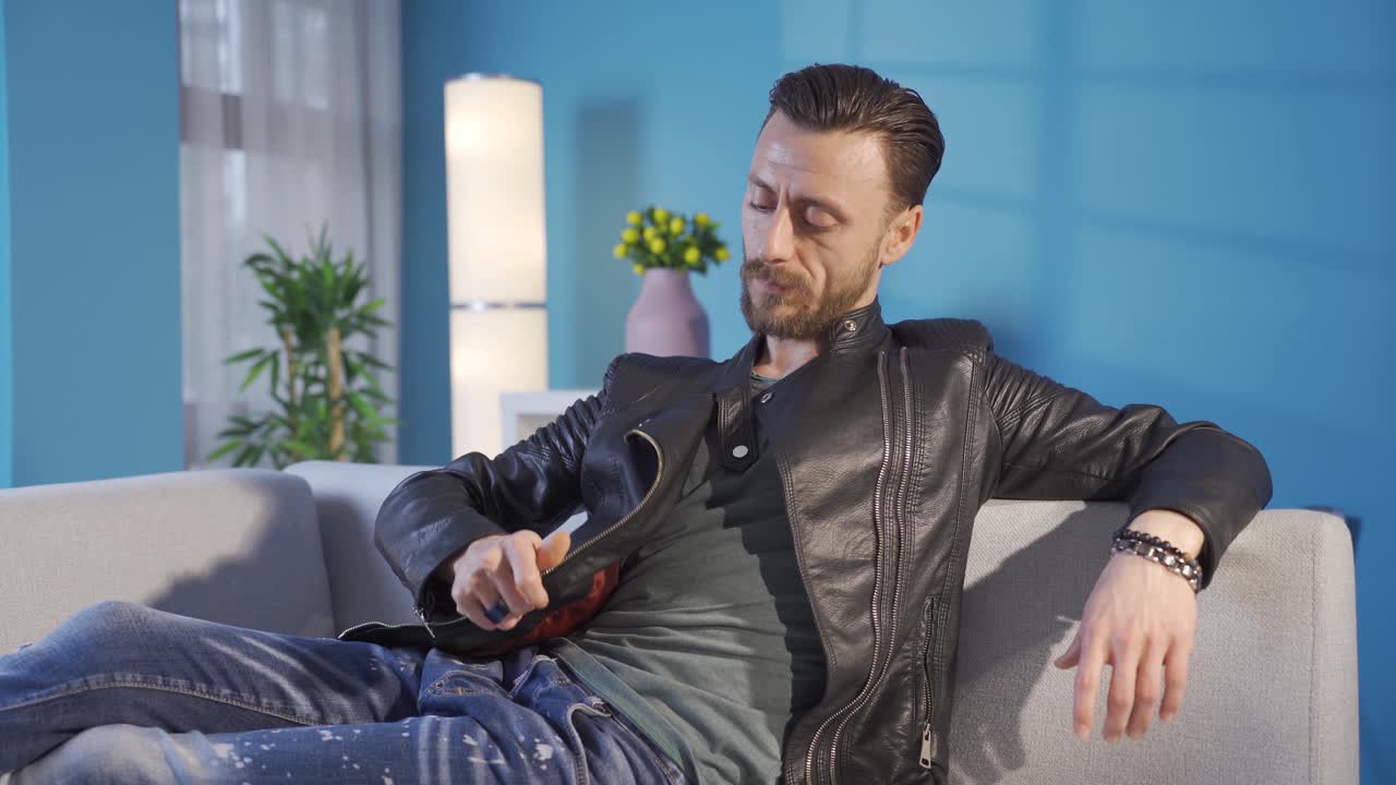 un joven adulto fresco y elegante sentado en el sofá de su casa y perdido en sus pensamientos profundos.