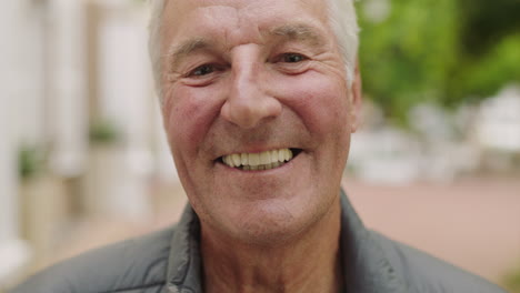 close up portrait of cheerful elderly caucasian man laughing happy looking at camera in urban city background