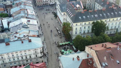 Tourists-walking-the-streets-of-Rynok-Square-in-Lviv-Ukraine-during-sunset,-surrounded-by-city-hall-and-European-buildings