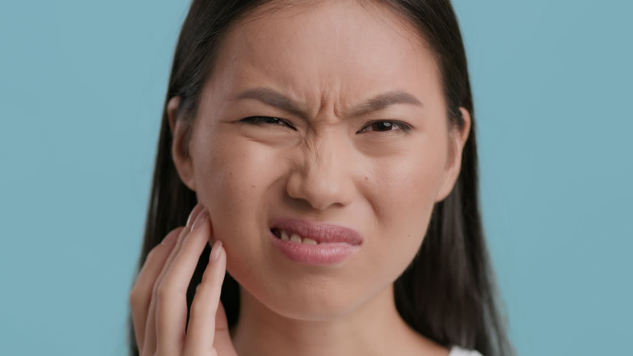 Young Asian Woman Suffering from Toothache or Jaw Pain