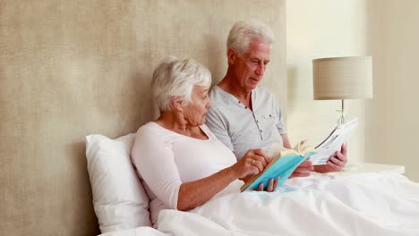 Senior-couple-sitting-in-bed-reading-