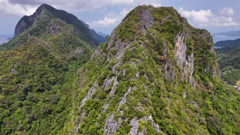 aerial drone footage of el nido, philippines, showcasing the steep mountains, lush tropical forests, and a serene island paradise. revealing shot.