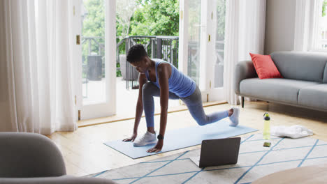 African-american-woman-performing-stretching-exercise-at-home