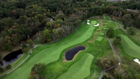 a high angle, aerial view over a well maintained golf course in westchester, new york during a cloudy day