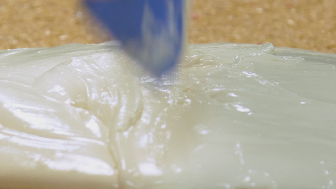 가단하고 끈적끈적한 아이싱을 펼칠 준비가 된 케이크 슬래브에 붓습니다.