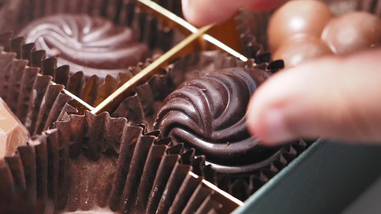 Person Selecting Chocolates from a Box