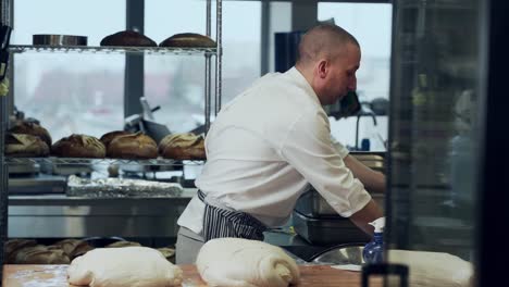 the baker cuts a spatula with wet bread dough