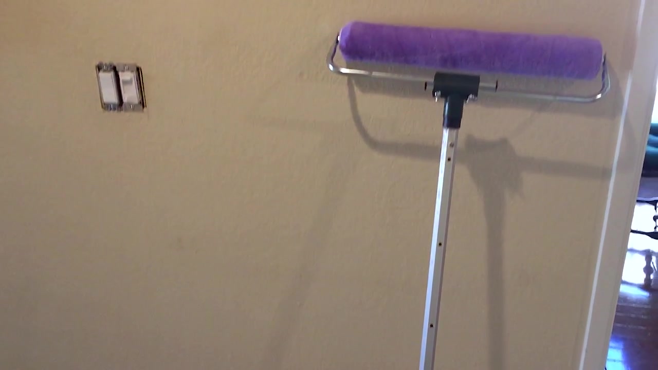Verfbak en roller tegen een beige afgewerkte muur, benodigdheden voor binnenhuisrenovatie.