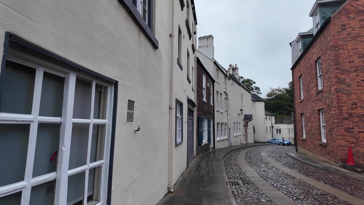 Stille historisk gade i Durham, England, med hvide bygninger og smalt fortov.