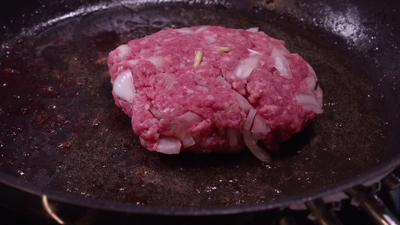 la grasa de hamburguesa de carne molida infundida con cebolla se coloca en una sartén caliente