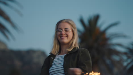 happy teenage girl playing with sparklers on beach at sunset having fun celebrating new years eve woman enjoying independence day celebration with fireworks