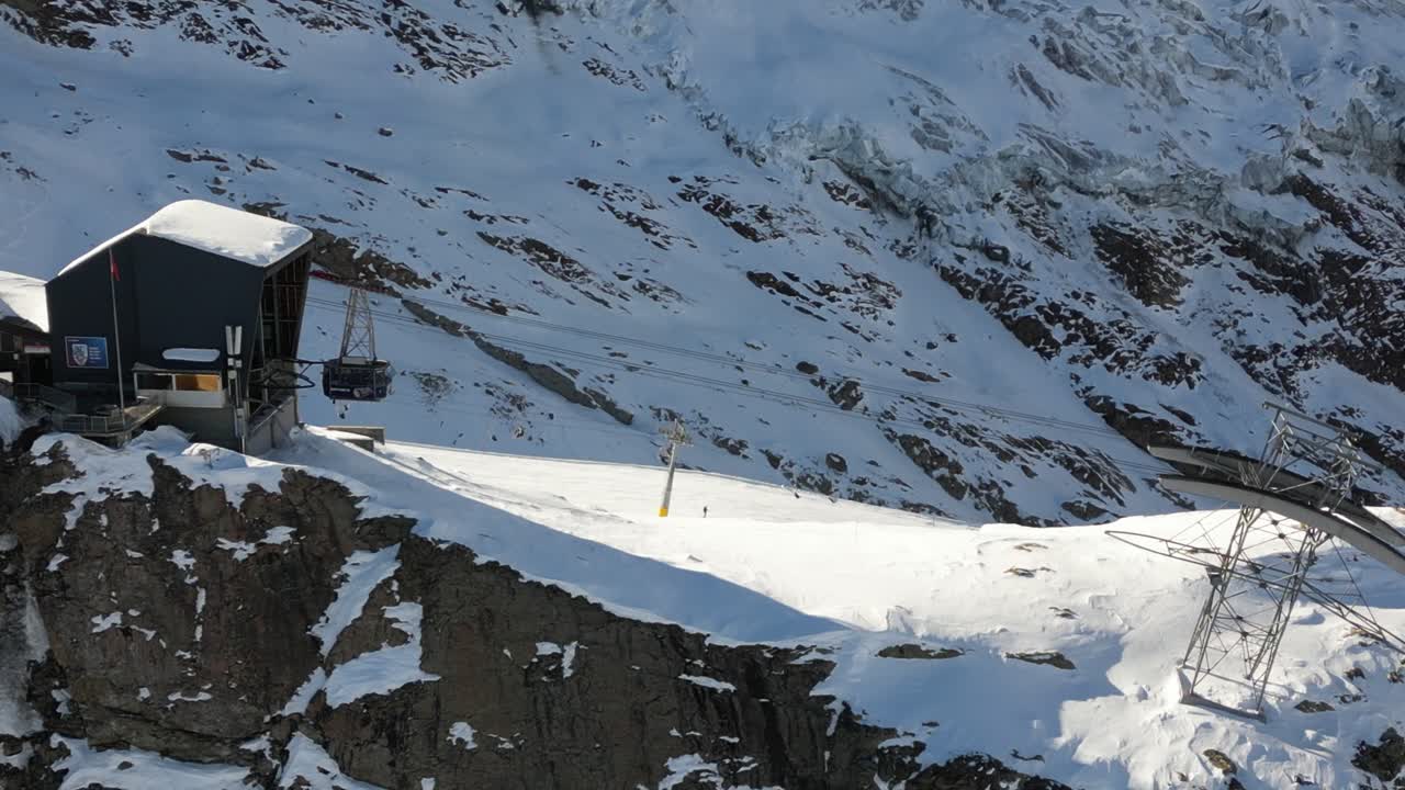 vista aérea, una góndola sale de un edificio en una montaña suiza en invierno
