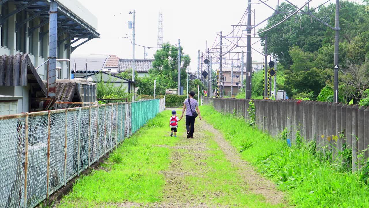 아들과 함께 있는 아버지는 도쿄의 키타야마 공원 옆에 있는 다른 산책로를 따라 걷고 있습니다.