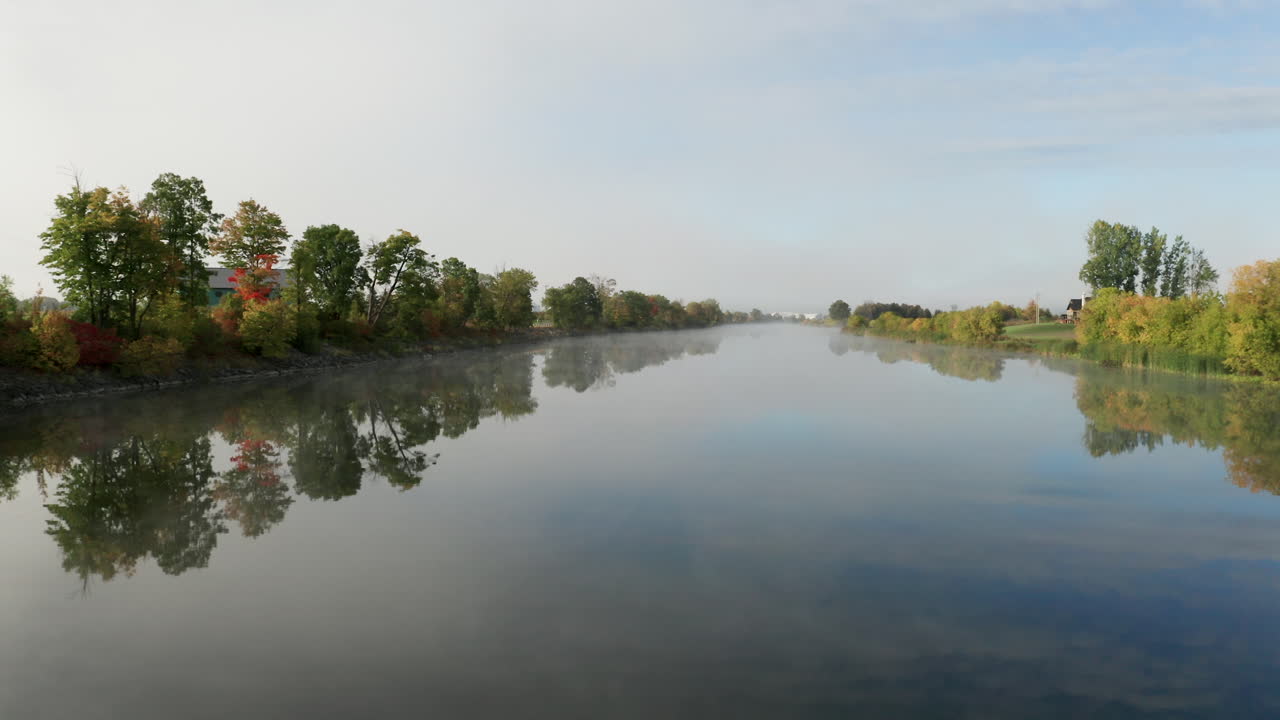 полет на малой высоте над гладкой ровной поверхностью реки при свете раннего утра