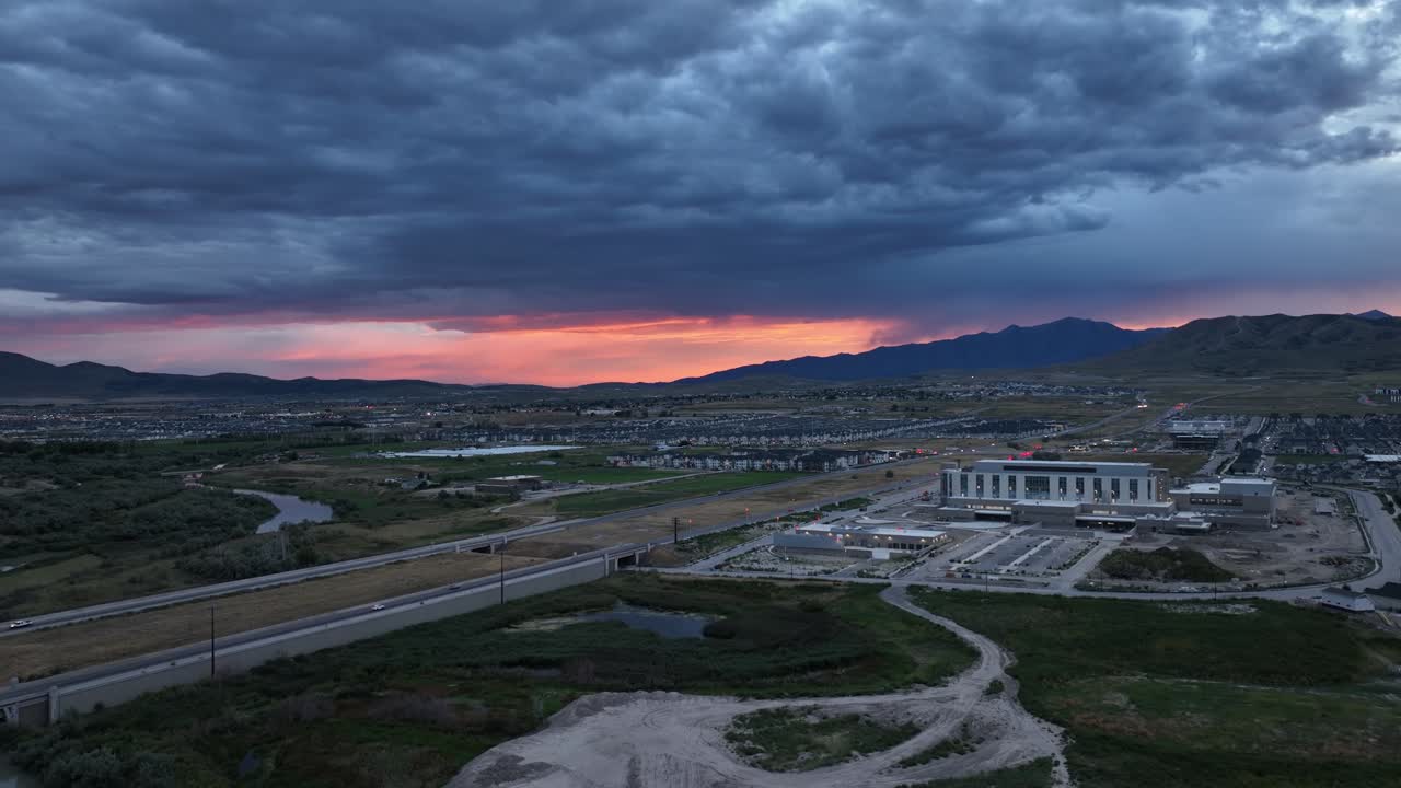 un atardecer colorido más allá de un cielo tormentoso en un valle suburbano - sobrevuelo aéreo