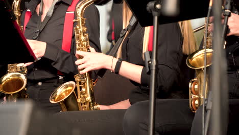 close up of music band in black dress playing song with golden trumpets