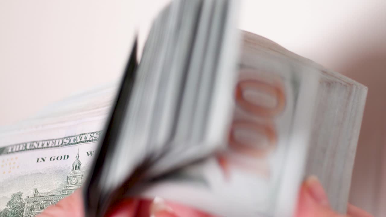 Primo piano di mani femminili che contano 100 dollari americani su sfondo bianco