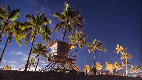 night timelaspe of haleiwa beach park with clouds and stars passing behind the lifeguard station before dawn breaks - oahu hawaii