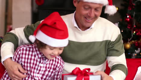 son giving father a christmas gift on the couch